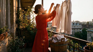 Video Face Swap sample: Face swap: a woman hanging laundry at golden hour, her motion kept, a new face swapped in.