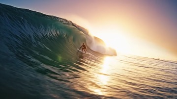 Veo 3.1 Extend sample: A surfer riding inside a golden-hour barrel, extended past the cut