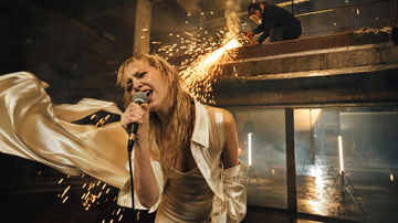 Music to Video sample: Illustration · A singer leans into a microphone in an empty industrial hall as sparks rain from a welder'