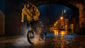 LoRA Chaining sample: Illustration · A cyclist in a mustard raincoat skids to a stop under a brick arch in heavy rain at night