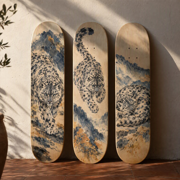 Three skateboard decks against a sunny wall, each painted with the same snow leopard in different poses.