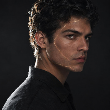 A portrait lit from one side, with faint luminous seams along the jaw where two faces meet.