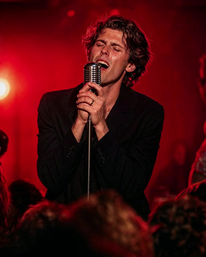 A singer mid-chorus on a club stage