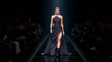 Kling 3.0 Turbo sample: A model in a sculptural black gown walks a spotlighted catwalk